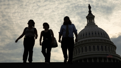 three students walking in front of the Capitol building, backlit